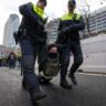 Climate change protesters in The Hague block highway, get detained and hauled away by bus